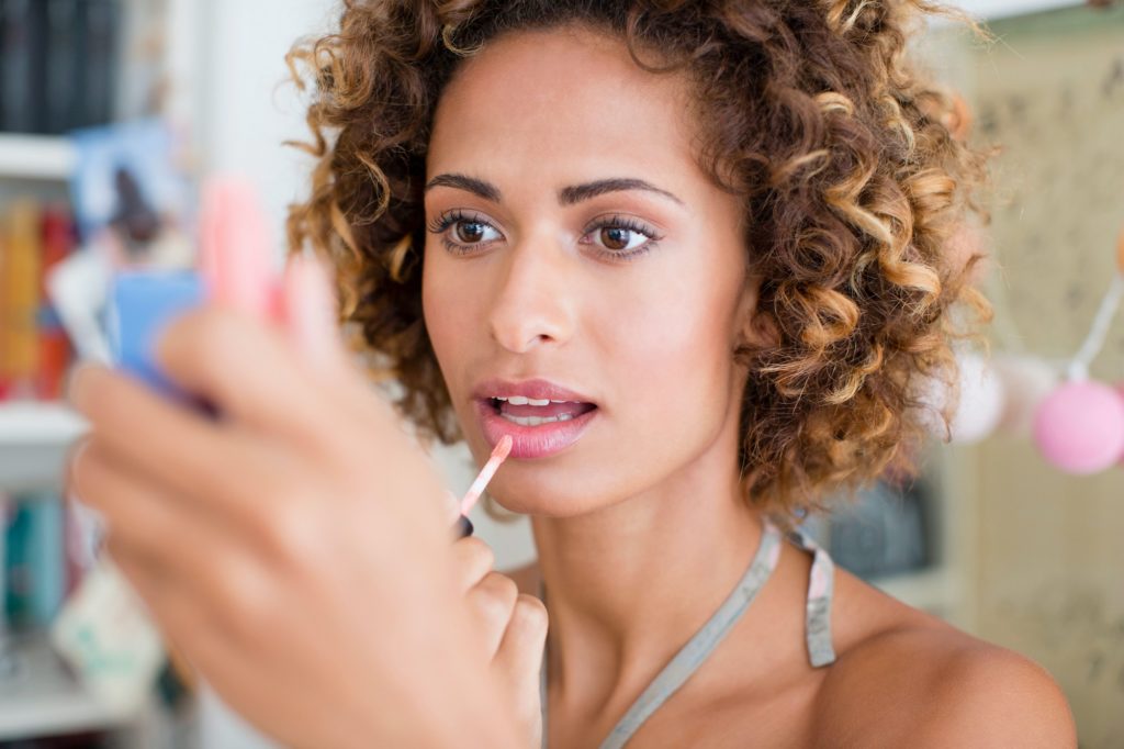 Woman applying make up in mirror