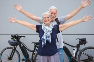 Cheerful couple of white-haired retired enjoying sport activity with their electric bicycles
